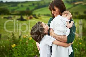 Hugging Mom with some warmth and love. a mother and her two little kids bonding together outdoors.