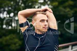 Stretch as far as your determination. a sporty young man stretching before a run outdoors.