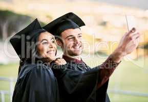 Look who made it to the top. two students taking a selfie together on graduation day.