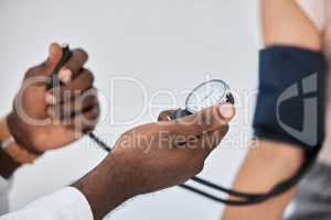 Blood pressure or hypertension test by a healthcare professional on a female at the clinic or hospital. Closeup of a medical worker or GP checking a hypertensive woman or patient using a tensiometer