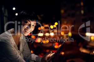 Living in the city means staying current. an attractive young woman using a digital tablet outside in the city at night.