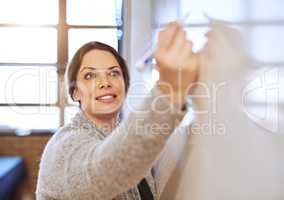 Shaping young minds for a better future. a cheerful schoolteacher writing notes on a whiteboard in class.