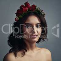 Enchanted beauty. Studio shot of a beautiful young woman wearing a floral head wreath against a grey background.