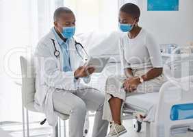 A doctor consulting a patient and talking to her about the covid virus using a tablet at the hospital or clinic. Female at her appointment or consultation with a healthcare or medical worker