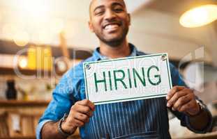 Were looking for people to join our amazing team. Portrait of a young man holding up a hiring sign in his store.