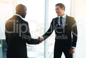 Allow me to extend a warm welcome. two businessmen shaking hands in an office.