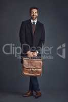 Ready for anything with this style. Studio portrait of a stylishly dressed young man carrying a bag against a gray background.