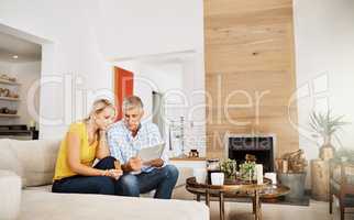 Buy whatever you like...a mature couple using a digital tablet while relaxing at home.
