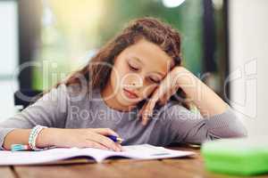 Trying to study but shed rather go play. a young girl doing homework inside.