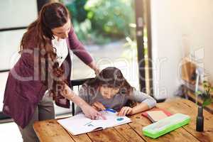 Read that to me. a young girl doing homework with her mother inside.