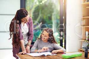 Great, you almost done with your homework. a young girl doing homework with her mother inside.