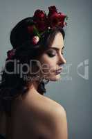 She is more beautiful than a rose. Studio shot of a beautiful young woman wearing a floral head wreath against a grey background.