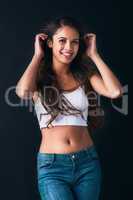 Confidence is the statement piece to this outfit. Studio portrait of an attractive young woman posing against a dark background.