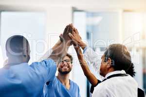 Celebrate every medical success. a diverse team of doctors giving each other a high five in a hospital.