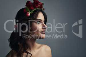 Destined to be desired. Studio shot of a beautiful young woman wearing a floral head wreath against a grey background.