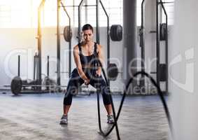 Fitness, exercise and battle ropes with a young woman athlete in a routine workout, exercising or training in a gym. Health, wellness and active lifestyle with an athletic, sporty and young female