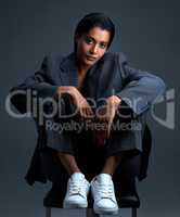 She knows how to wear a suit properly. Studio shot of a beautiful young woman posing against a dark background.