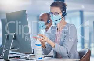 Sanitize, hygiene and compliance with covid19 regulations at call center with crm agent cleaning workstation. Woman working in customer service, making sure to leave desk fresh for the next operator