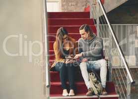 Using technology to prep for finals. Full length shot of two young university students studying while sitting on a staircase on campus.