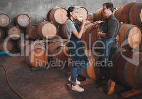Wine distillery owners tasting the produce in the cellar standing by the barrels. Oenologists or sommeliers drinking a glass of chardonnay or sauvignon blanc inside a winery testing the quality