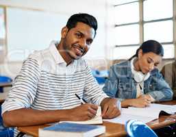 Getting through my studies one subject at a time. Cropped portrait of a handsome young university student taking notes while sitting in class.