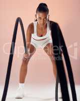 Fitness, exercise and woman doing battle ropes workout in her healthy training routine in a sports studio. Girl, energy and athlete in active motion working on cardio for muscular strength action