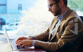 Hes one focused individual. a handsome businessman working on a laptop while sitting at his desk in the office.