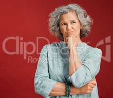 Thinking, confused and wondering woman looking puzzled, unsure and uncertain about choice, decision and idea in mind against studio red background. Thoughtful senior woman with goofy frown expression