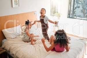 Children, fun and energy by playing siblings jumping, bonding and enjoying a game on bed at home together. Kids laughing and having fun, sharing playful moments of childhood, celebrate free weekend