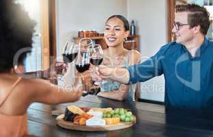Friends, fun and celebration with diverse group toasting with red wine to good news, bonding at a restaurant. Young friends reunion, happy to be together and enjoy wine tasting with charcuterie board