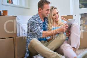We can order tons of furniture online. a young couple using a digital tablet while moving house.