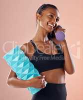 Fitness, active and healthy woman holding a dumbell, foam roller and smile after sports training against studio background. Happy fit lady feel slim, happy and cheerful after gym, workout or exercise