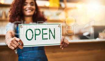 Time to start a new day. Portrait of a young woman holding up an open sign in her store.