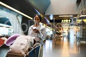 Going through her final checklist. an attractive young woman sending a text while standing in an airport.