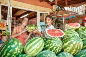 Looks like watermelons are in season. Cropped portrait of a mother and daughter working at a farm stall.