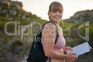 Outdoors and loving it. Portrait of a young woman reading a map while out on a hike.