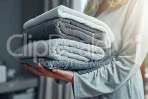 Laundry day. Closeup shot of an unrecognizable woman carrying a pile of towels while doing laundry at home.