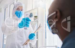 Healthcare worker, checking the temperature of male covid patient for safety against virus pandemic, wearing protective suit. Medical doctor in a hazmat suit, using a thermometer to prevent outbreak