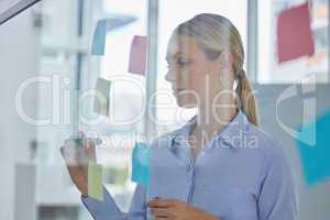 Creative, schedule and planning of a female designer writing plans for tasks or ideas at the office. Woman in design working on a project plan or strategy to organize work and productivity.