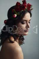 The goddess rises with roses in her hair. Studio shot of a beautiful young woman wearing a floral head wreath against a grey background.
