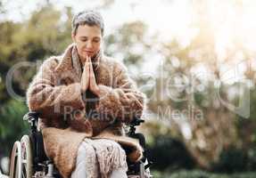 All I need is a miracle right now. a senior woman holding her hands together in prayer while sitting in her wheelchair outside.