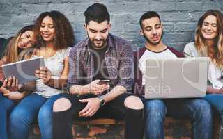 Entertainment on demand for the digital generation. a group of young friends using their wireless devices together outdoors.