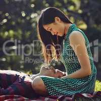 The perfect spot for some romance. an affectionate young couple relaxing together on a picnic blanket in the park.