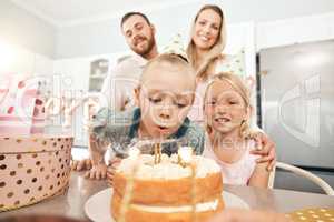 Children birthday party, cake and candles for blowing out with mother, father or sister in home kitchen. Fun, excited or happy kids celebrating, enjoying and having fun with parents on special event