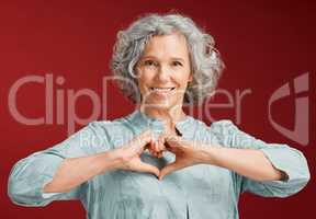 Love, heart and health retired woman with loving emoji sign, icon or symbol showing care or affection on red valentines day studio background. Grey, senior or pensioner with a trendy emoticon pose