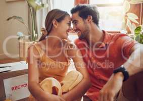Happy and in love couple sitting together, bonding and spending quality time in a new apartment, flat or house. Homeowner, loving man and woman relax, care free and enjoy a day inside with a smile