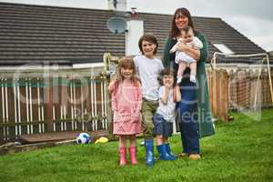 The happiest of families. Portrait of a mother and her four little children standing on the lawn outside their house.