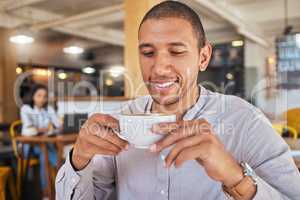 Man enjoying a cup of coffee, while smiling and sitting at a cafe relaxing. Businessman drinking tea or caffeine at restaurant. Relaxed and happy male holding a mug or beverage in a coffee shop