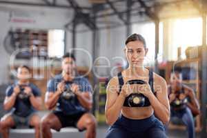 Kettlebell squats, fitness and training group of healthy people living an active health, wellness and body or weight watching lifestyle. A sports team doing a workout or exercise in a gym class