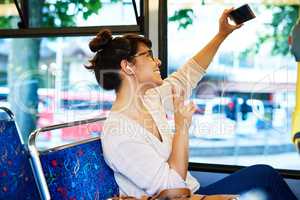 One for the road. an attractive young woman taking selfies with her smartphone while sitting on a bus.
